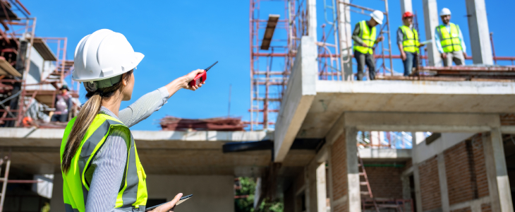 female construction worker pointing at three male construction workers