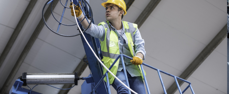 man with hard hat reaching for somethign high up