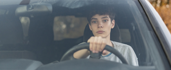 Young boy driving a car with a distraught face