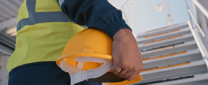 Man walking up the stairs holding a hard hat