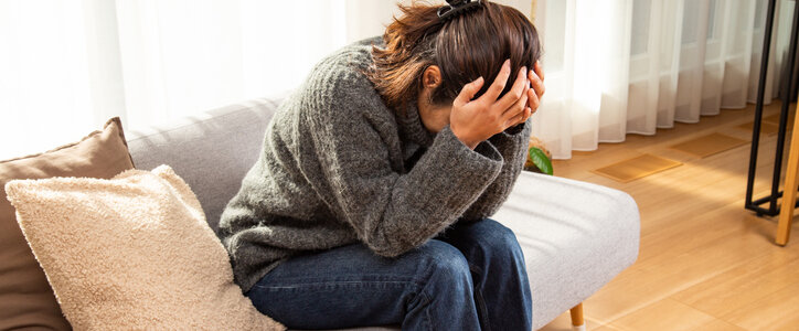 Woman holding he head while sitting down