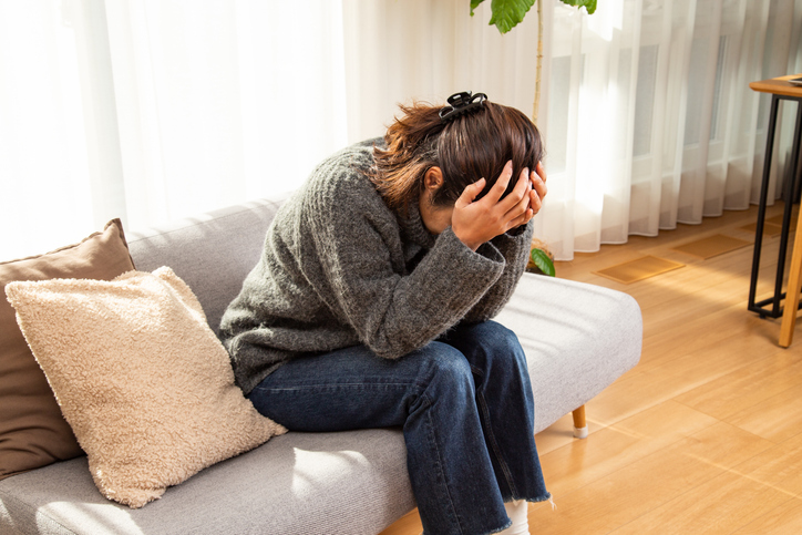 Woman holding he head while sitting down