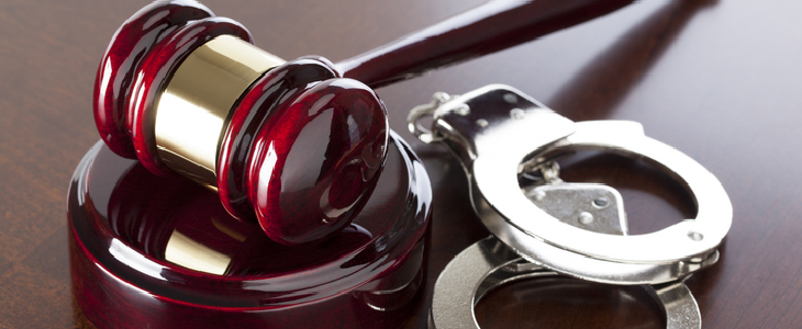 Red gavel and handcuffs on a table