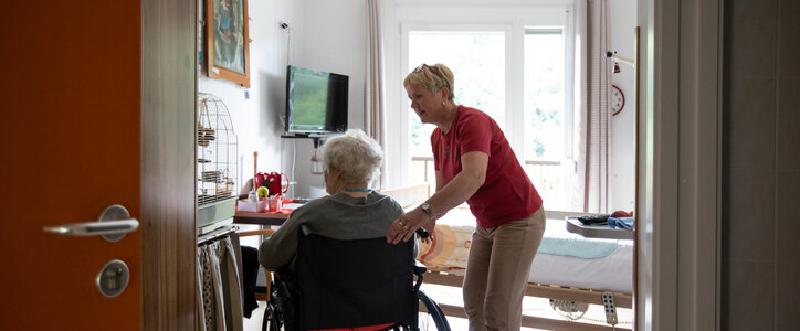 Elderly man in a wheelchair being assisted by a nurse