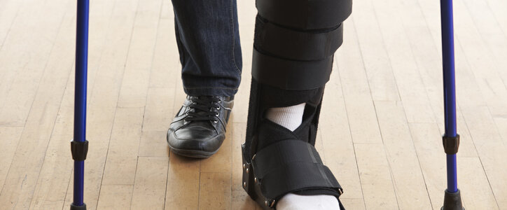 Man walking with a leg cast using crutches to support him.