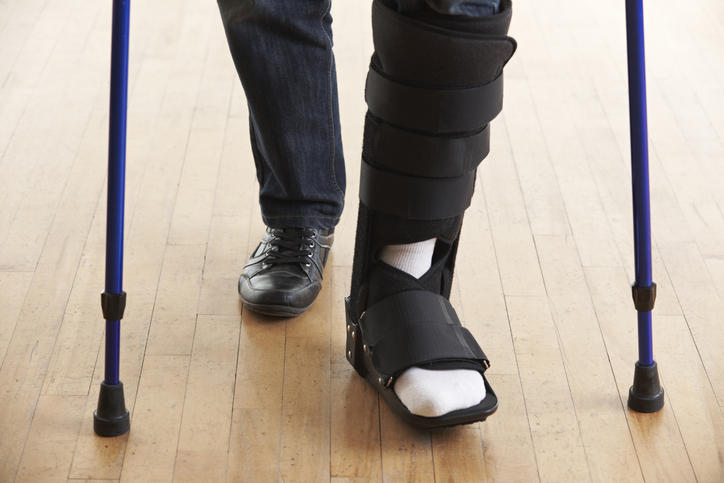 Man walking with a leg cast using crutches to support him.