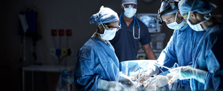 Team of surgeons and anesthesiologists performing a surgery in an operating room.