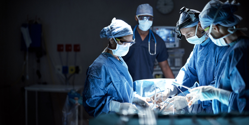 Team of surgeons and anesthesiologists performing a surgery in an operating room.