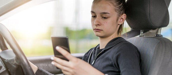 Young female student driver texting while driving.