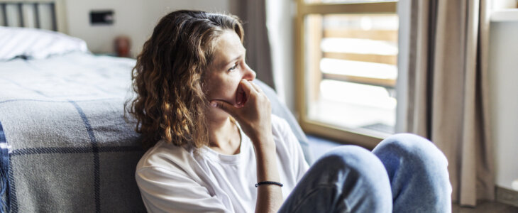 Woman sitting by her bed, stressed, with PTSD