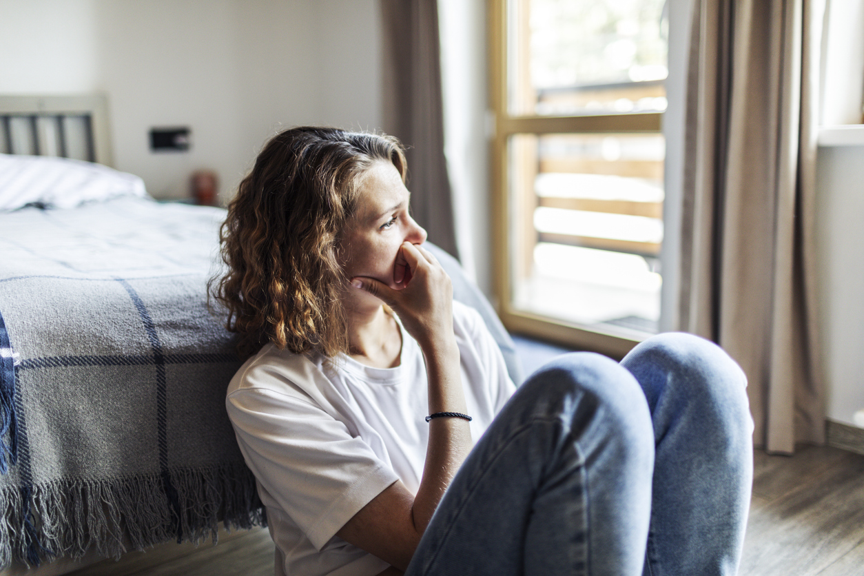 Woman sitting by her bed, stressed, with PTSD