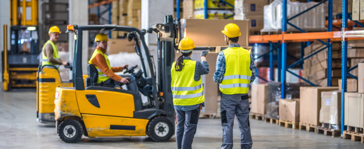 Male and female worker working in warehouse with a forklift.