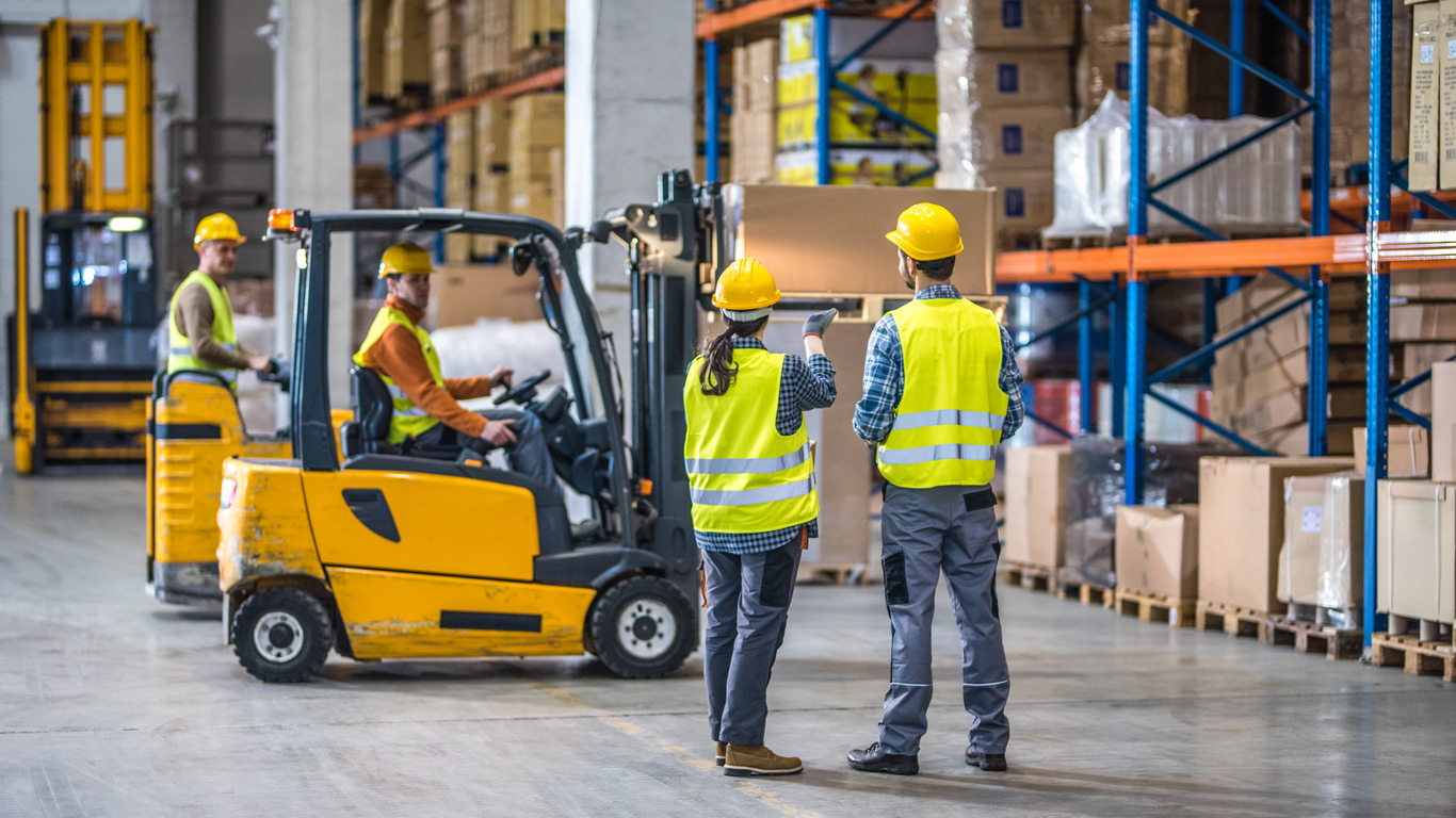 Male and female worker working in warehouse with a forklift.