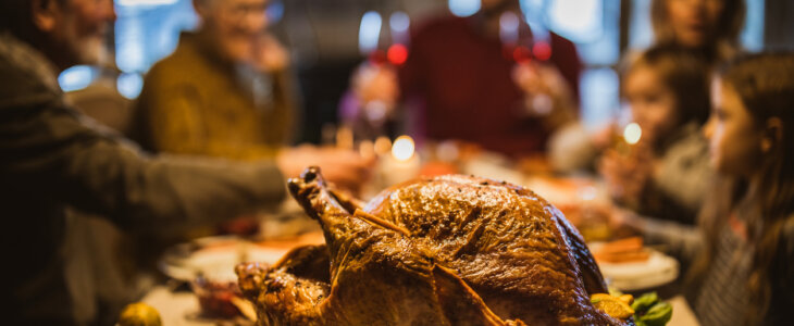 Close up of Thanksgiving stuffed turkey on dining table with family in the background