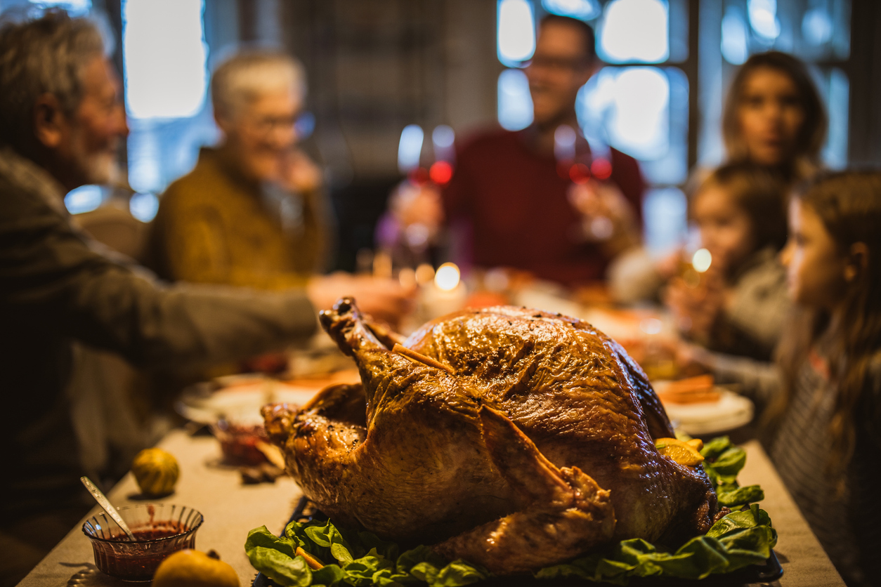 Close up of Thanksgiving stuffed turkey on dining table with family in the background